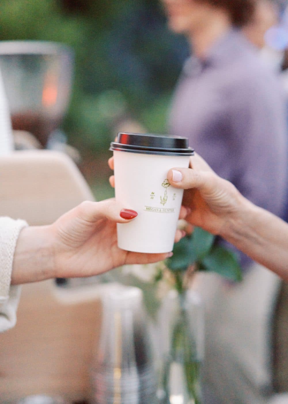 Barista handing a custom-branded cup to a guest at a corporate coffee catering event