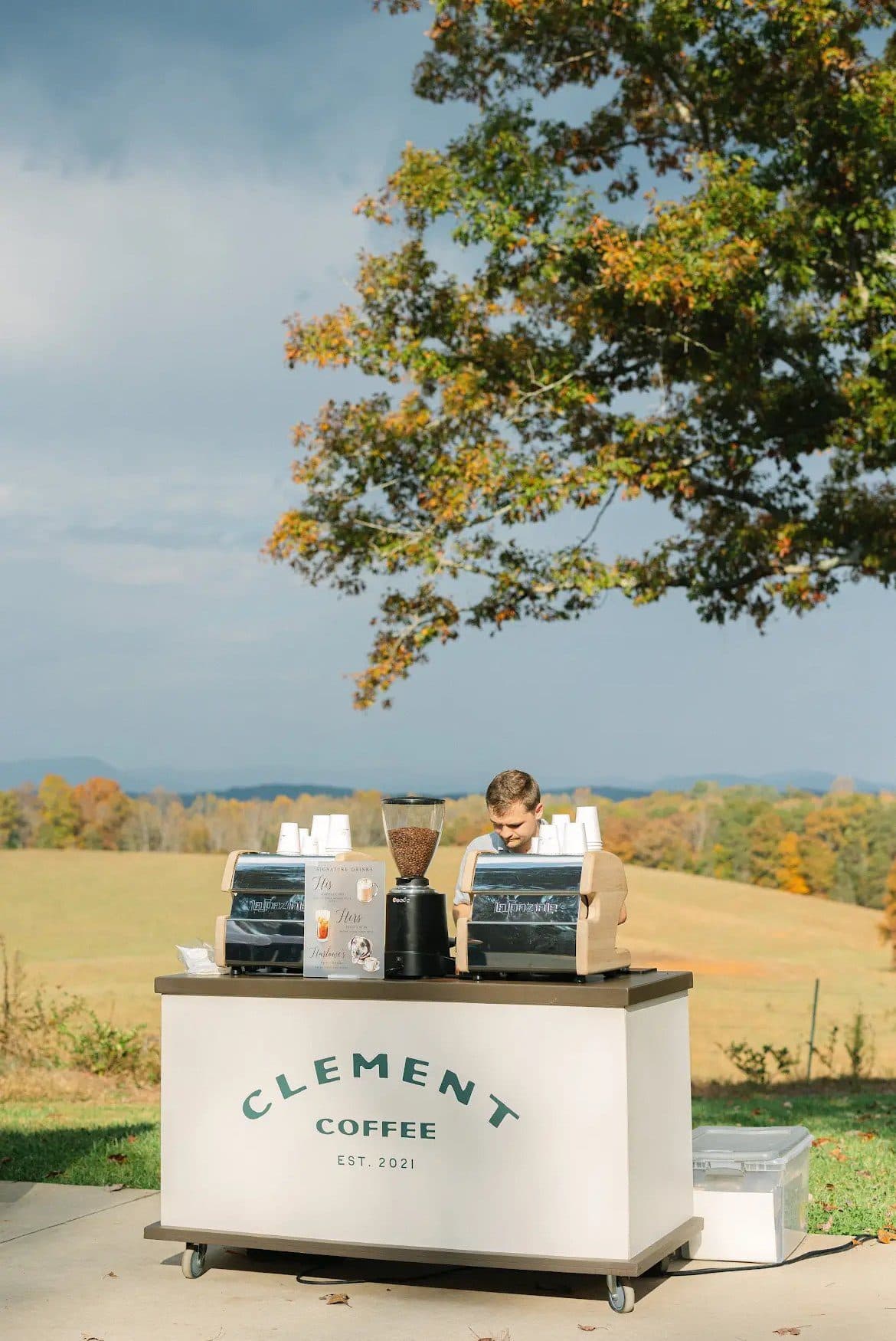 Clement Coffee mobile coffee cart set up outdoors on a hillside for an event — a coffee cart, not a coffee truck
